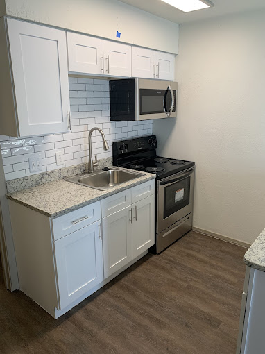 a kitchen with white cabinets and stainless steel appliances at The Kings Lofts